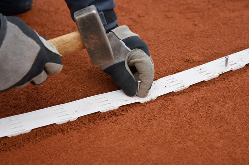 Weiße Linie wird mit Hammer und Nägeln auf roter Asche befestigt